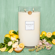 Lit Gardenia Tuberose Big Ass Candle with florals and lemons surrounding it