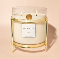 Gold candle holder with a lit unscented Baby Big Ass Candle resting in it.