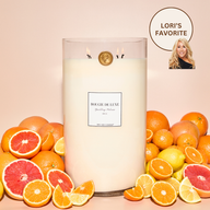 Lit Sparkling Paloma Big Ass Candle with cut up citrus fruit surrounding it