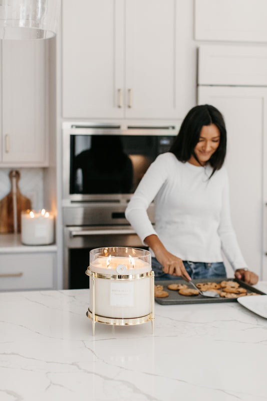 Lifestyle shot of model baking cookies beside a flickering candle.