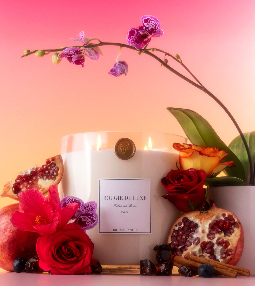 Decorative candle with flowers and pomegranates on a pink background