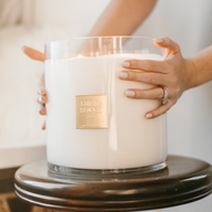 Amber Rouge Baby Big Ass Candle with women's hands wrapping around edge of candle.
