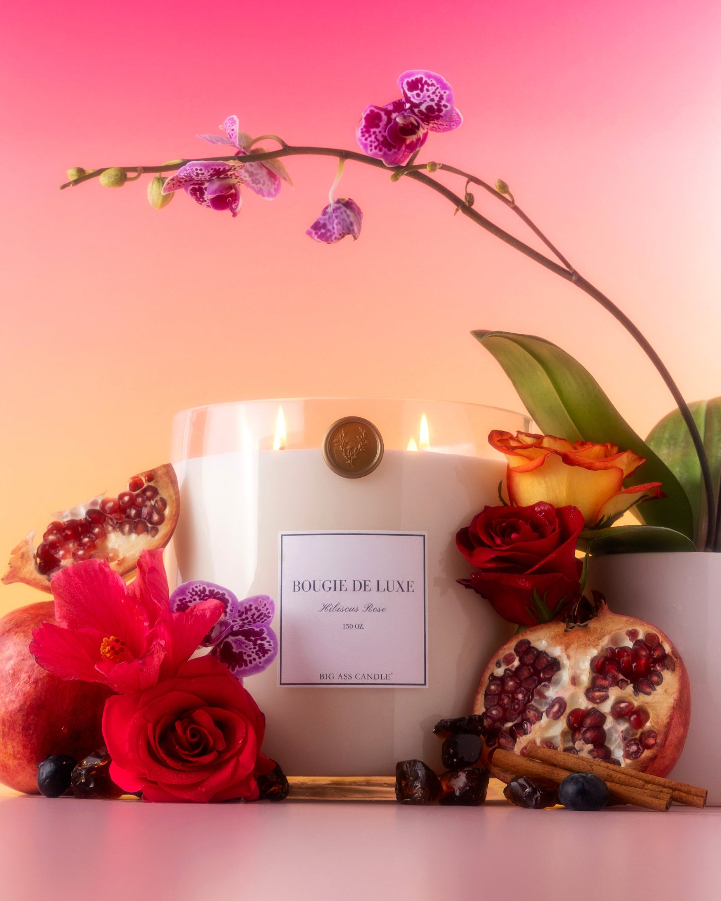 Candle with flowers and pomegranates on a gradient pink and orange background