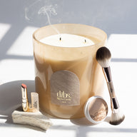 Dibs candle with makeup items on a light background