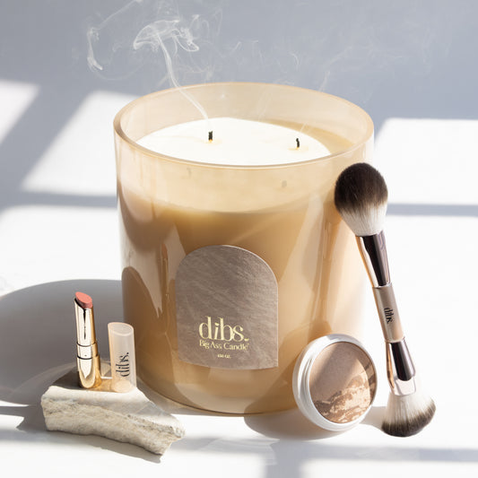 Dibs candle with makeup items on a light background