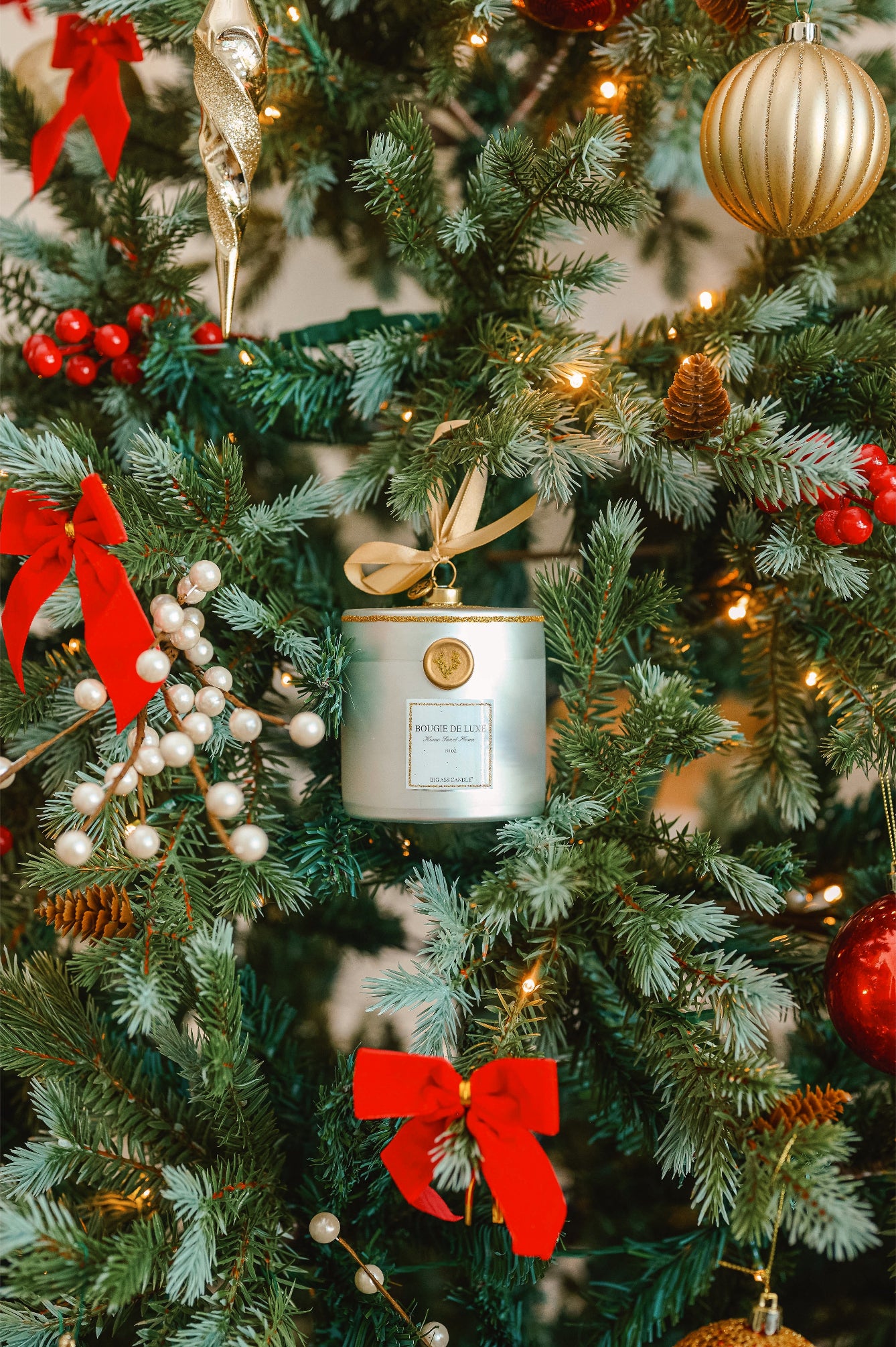 Decorative candle ornament with a bow on a Christmas tree.