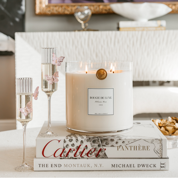 Candle on a decorative surface with framed artwork in the background